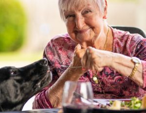 Someren Glen Senior Living Community in Centennial, CO - elderly woman eating dinner with dog 435x336